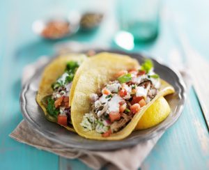 mexican authentic carnitas tacos with sour cream and corn tortilla shot with extreme selective focus